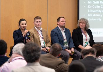 Four participants sit in a row during a panel discussion session