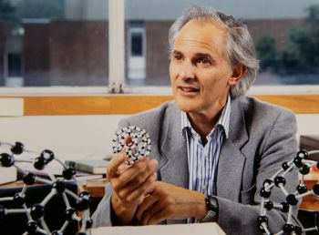 Professor Sir Harry Kroto holding a model of a buckyball