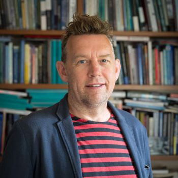Peter Newell in his office posing with books behind him