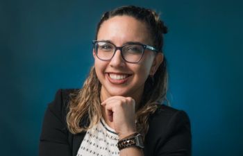 Portrait photograph of Lilly Soto Cintrón. Lily is holding her chin in her hand.