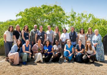 A photo showing the Careers and Entrepreneurship team posing outside, with trees in the background. The team are smiling and two people are holding the Graduate Futures Awards trophies.