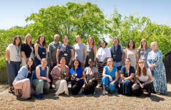 A photo showing the Careers and Entrepreneurship team posing outside, with trees in the background. The team are smiling and two people are holding the Graduate Futures Awards trophies.