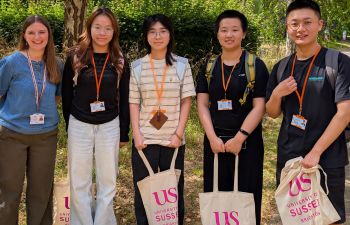 Group of international students with Sussex bags under a tree