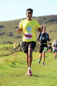 Marathon runners runing along a green coastal path