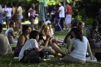 Group of students sitting on the grass, talking and eating