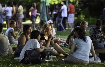 Group of students sitting on the grass, talking and eating