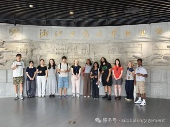 Students standing in front of moulded marble wall with gold Chinese lettering