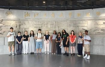 Students standing in front of moulded marble wall with gold Chinese lettering