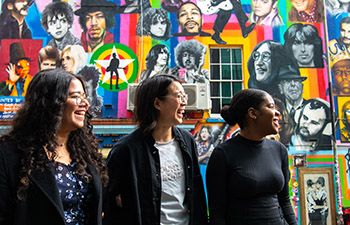 Students in Brighton in front of a graffiti wall