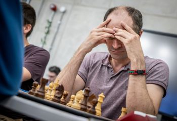 Chess player with hands on head, ready to make next move.
