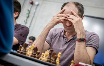 Chess player with hands on head, ready to make next move.