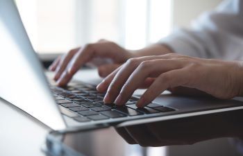 Hands typing on a laptop keyboard