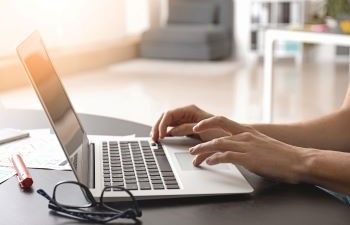 Hands typing on a laptop keyboard