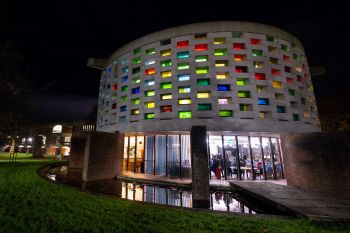 A nightime picture of the Meeting House with people meeting and showing empathy to each other