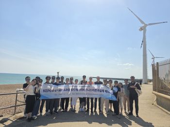 Korea Electric Power Corporation employees pose with banner besides wind turbines on Sussex coast
