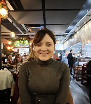 A dark-haired woman seated in a restaurant and smiling