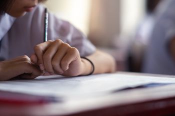 Close up of a school pupil writing at a desk