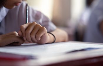 Close up of a school pupil writing at a desk