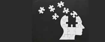 A white silhouette head with jigsaw pieces flying out of it on a black background