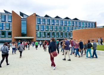Students walking towards the Business School building across a plaza