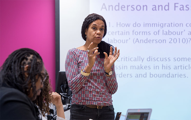 ICON: lecturer giving a talk in front of a smartboard