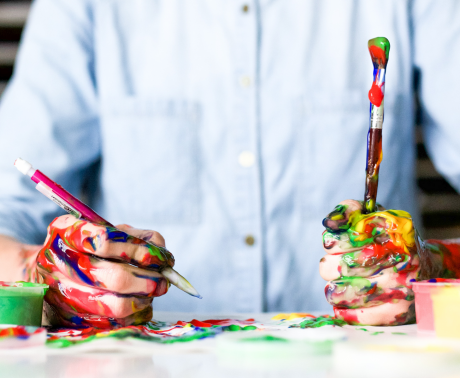 A man wearing a shirt writing with paint over his hands