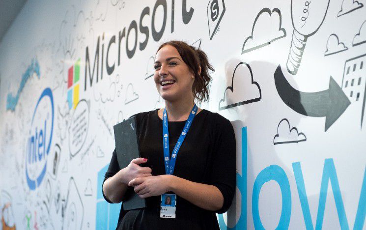 A placement student smiles in front of the Microsoft sign