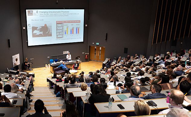 Large crowd of attendees in lecture hall listening to keynote presentation