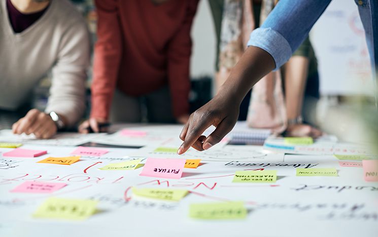 peoples hands sorting through post-it notes and planning around a table