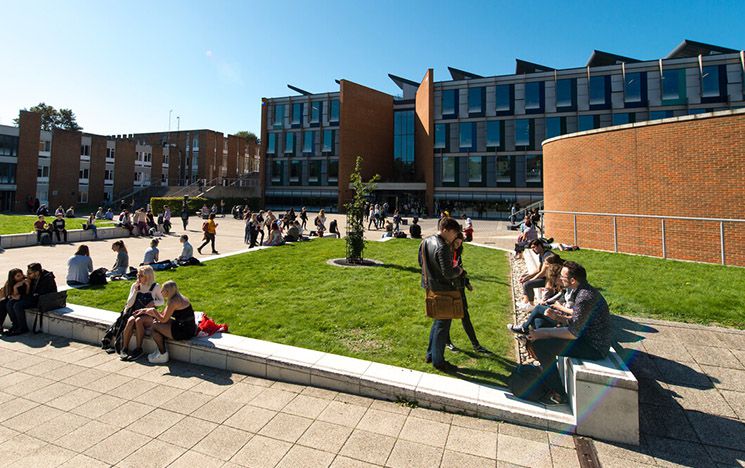 Students sat on the grass on a sunny day with Jubilee building in the background