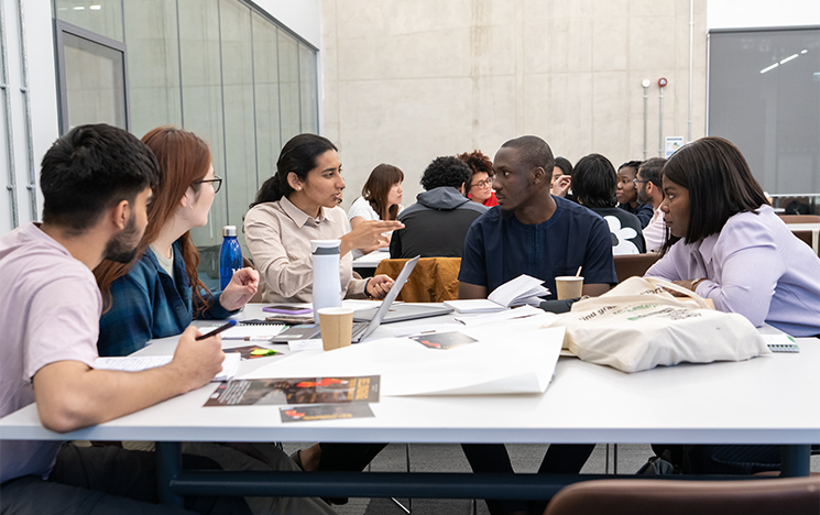 Postgraduate students sitting around a table having a discussion