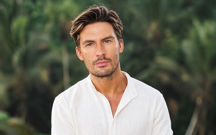 A man in a white shirt against a green background.
