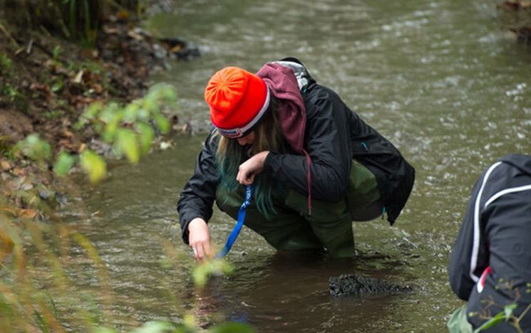 A student surveys a river using specialist equipment