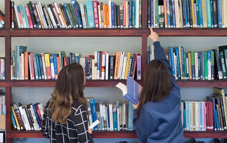 Two students browsing book shelves in the Global Studies library