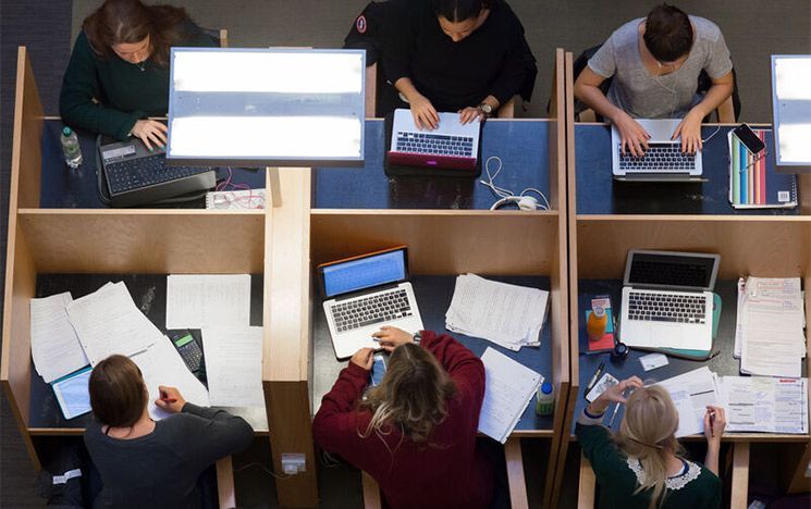 An aerial view of students sitting at desks in a library study area