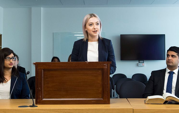 One person speaking from desktop lecturn with a person on each side of them