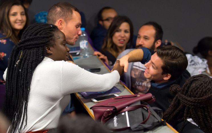 International students shaking hand in a lecture theatre