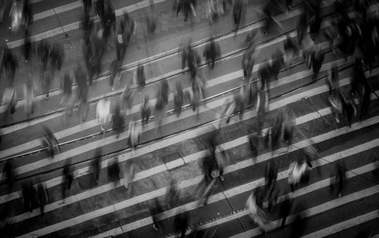 a crowd people rushing in all directions and crossing a busy street