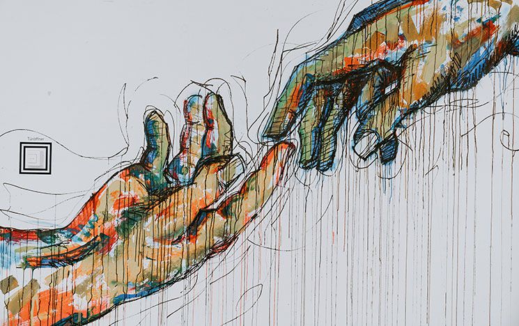 two painted multicoloured hands reaching out to touch each other