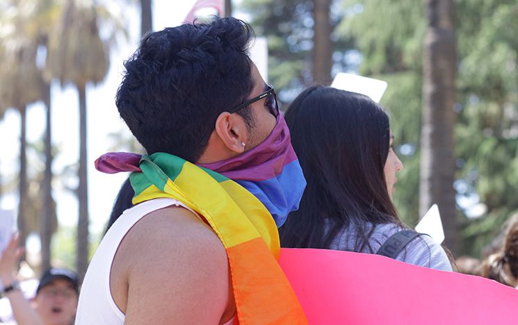 Protestors wrapped in a rainbow flag