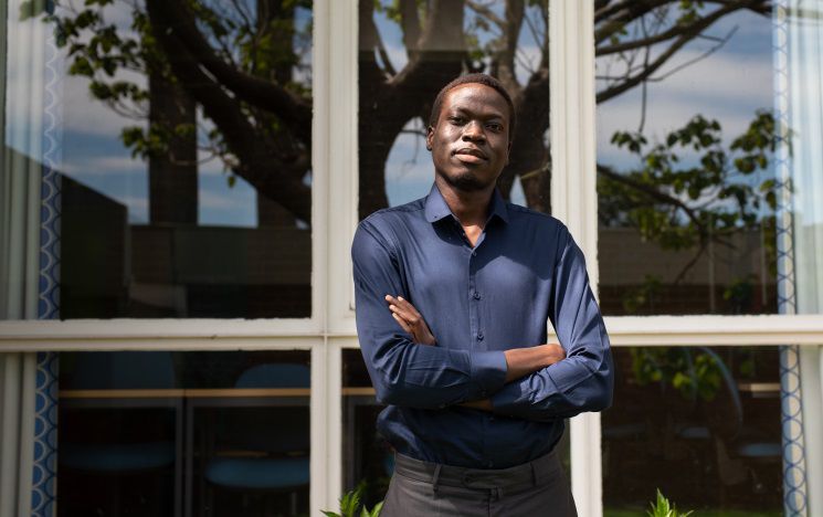 Godfrey standing with arms crossed in front of windows