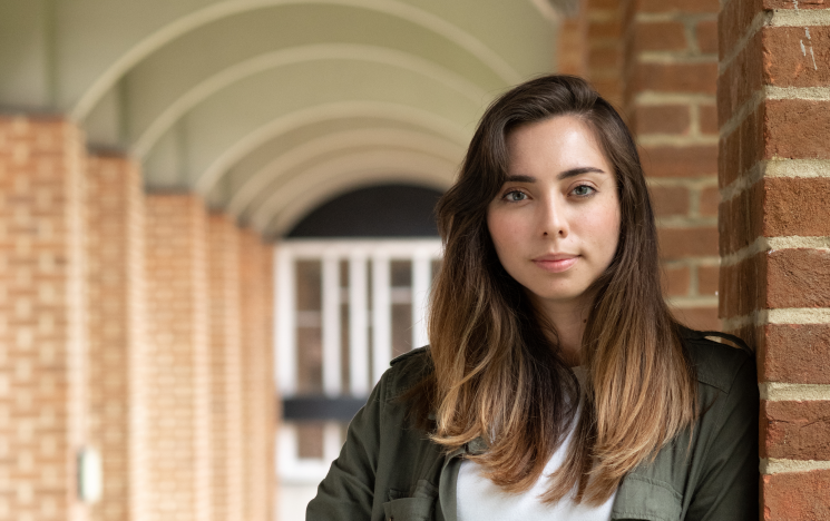 Mariana standing outside smiling in front of University red brick building