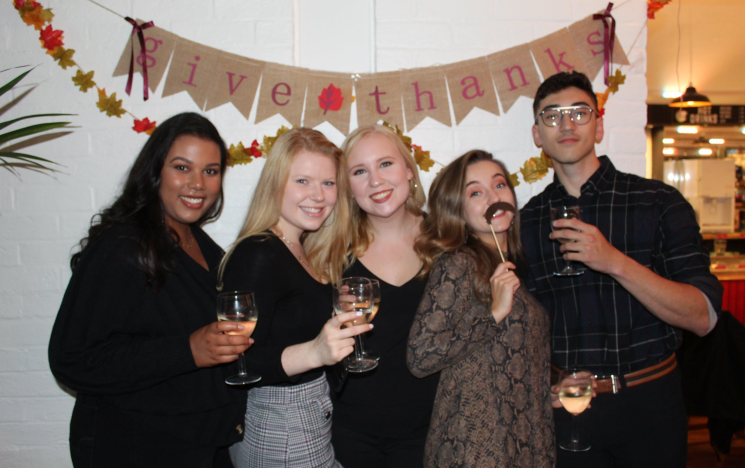 Five Canadian students with drinks pose in front of the camera