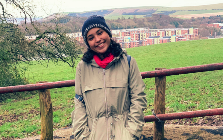 A student stands infront of the campus and local countryside on an overcast day