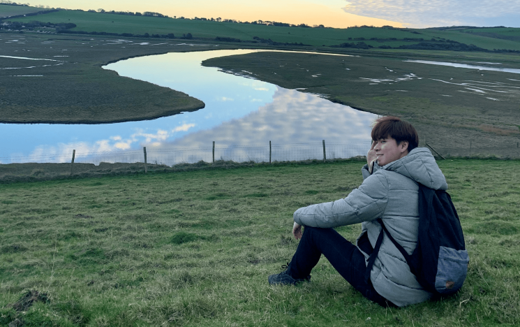 A student in winter looks over a winding river at sunset