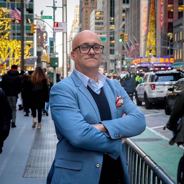 Benedict Brook stands still for a photo on a bustling New York City street.