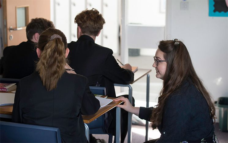 A trainee teacher helping her students during placement