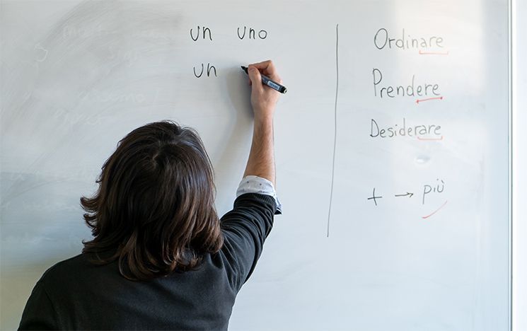 A tutor writes in Italian on a whiteboard