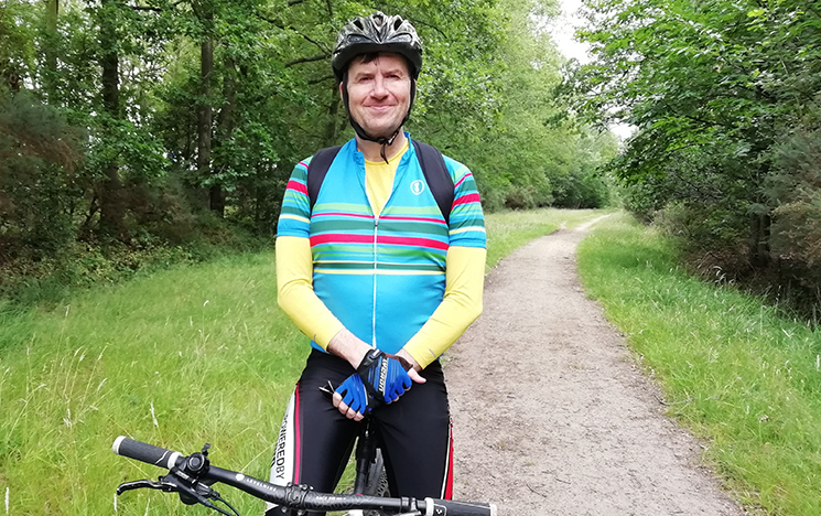 A man in cycling gear standing with his bike.