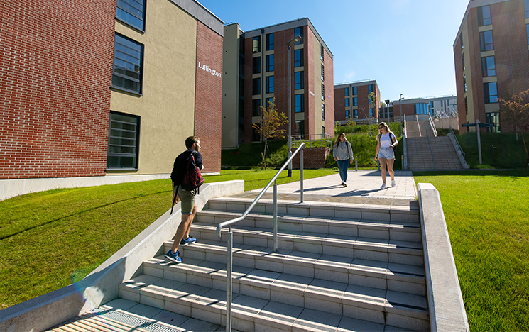 Students walking up steps on campus amongst campus buildings
